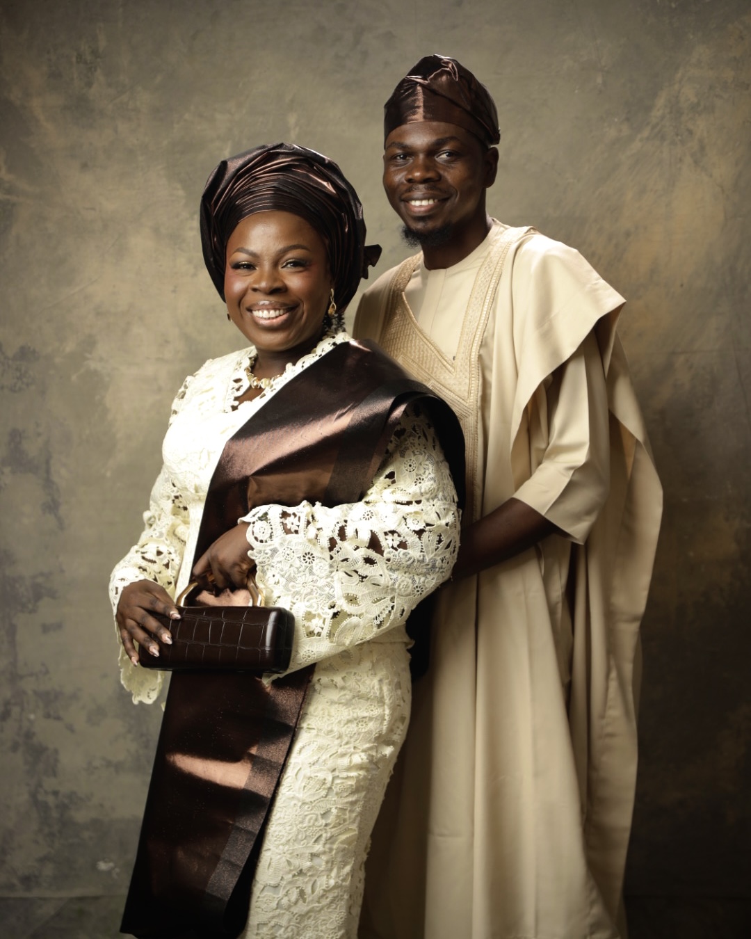 Adébọlá and Oyèkúnlé smiling together in cream and brown traditional attire